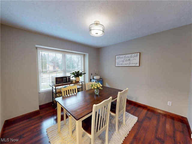 dining room with a textured ceiling, baseboards, and dark wood-style flooring