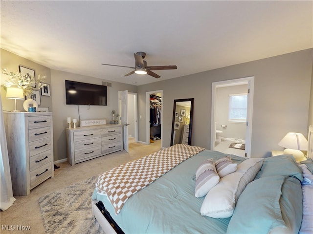 bedroom featuring ensuite bath, ceiling fan, a closet, light carpet, and a walk in closet