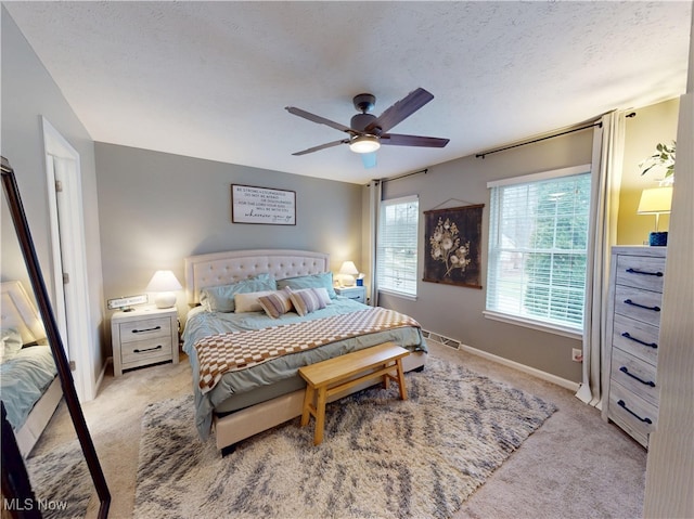 bedroom with baseboards, light carpet, a textured ceiling, and a ceiling fan