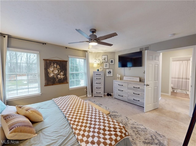 bedroom with visible vents, light colored carpet, a textured ceiling, and baseboards