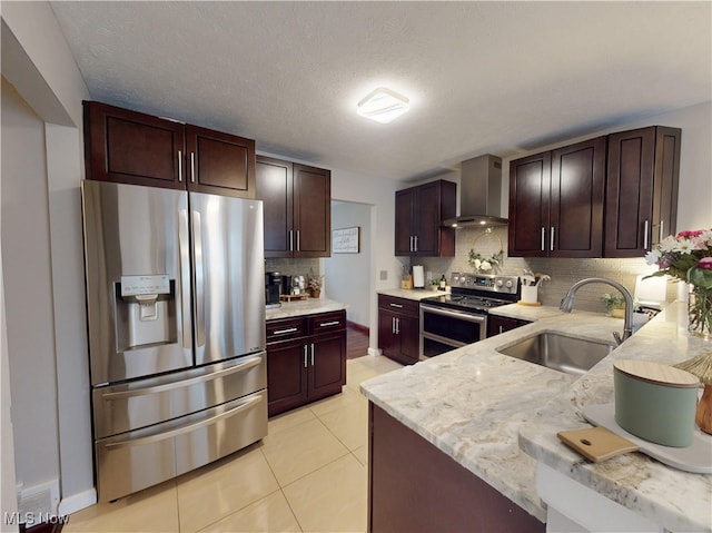 kitchen featuring a sink, appliances with stainless steel finishes, wall chimney exhaust hood, light tile patterned floors, and decorative backsplash