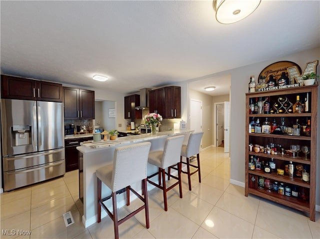 kitchen featuring light tile patterned floors, a kitchen breakfast bar, light countertops, and stainless steel fridge with ice dispenser