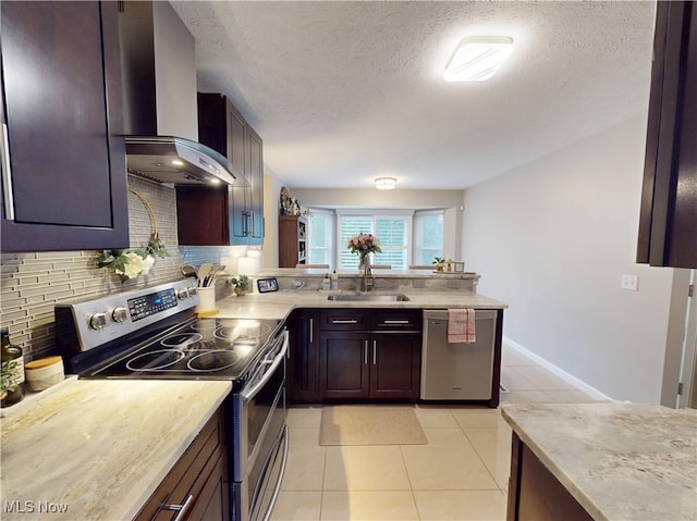 kitchen with a sink, tasteful backsplash, appliances with stainless steel finishes, wall chimney exhaust hood, and light countertops