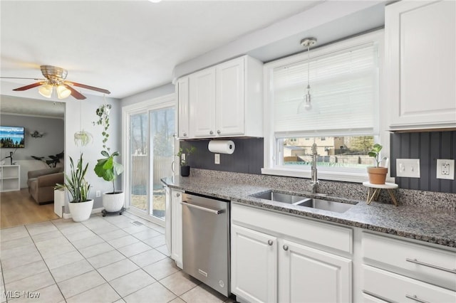 kitchen with stainless steel dishwasher, white cabinetry, a wealth of natural light, and a sink