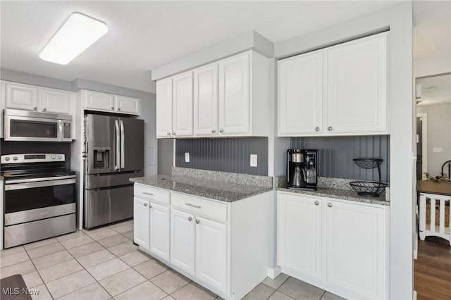 kitchen with light tile patterned floors, white cabinetry, stainless steel appliances, and light stone countertops