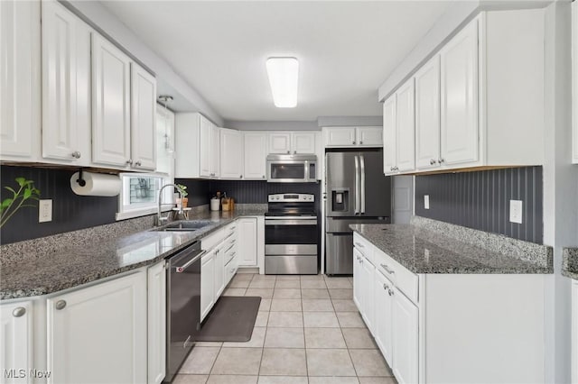 kitchen with a sink, stainless steel appliances, white cabinetry, and light tile patterned floors