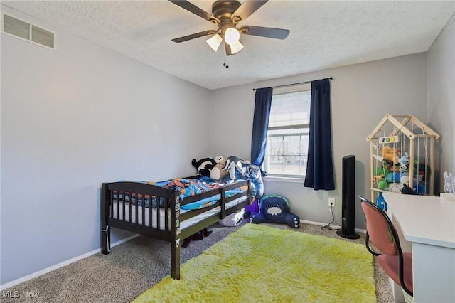 carpeted bedroom with visible vents, a textured ceiling, and baseboards