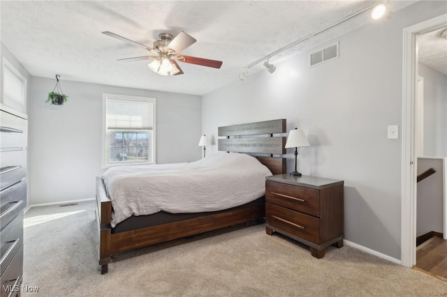 bedroom with visible vents, light colored carpet, a ceiling fan, and baseboards