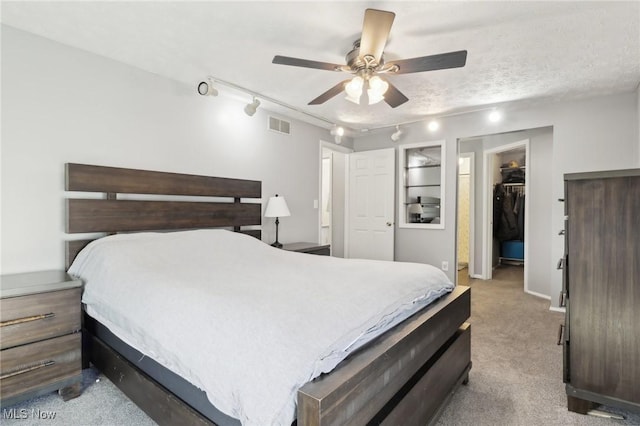 bedroom featuring visible vents, track lighting, a walk in closet, carpet flooring, and a closet