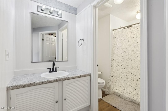 full bathroom featuring curtained shower, toilet, vanity, and wood finished floors