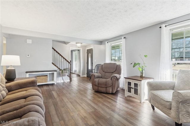 living room featuring stairway, a textured ceiling, and wood finished floors