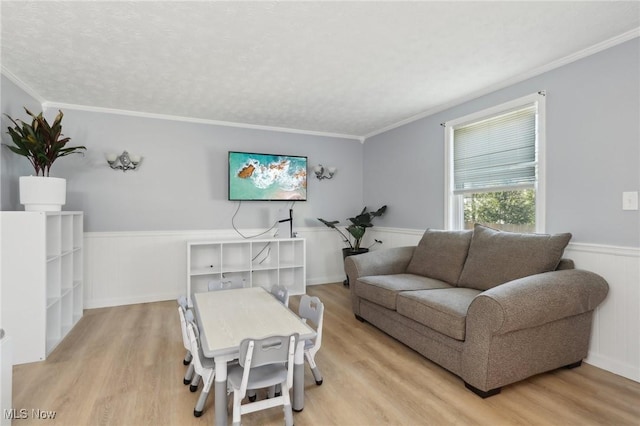 living area featuring a wainscoted wall, crown molding, and light wood-type flooring