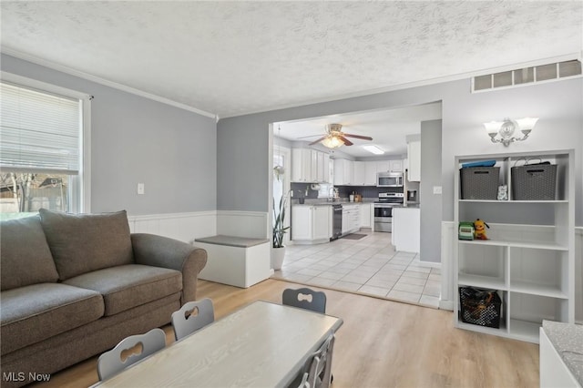 living area with visible vents, a textured ceiling, a healthy amount of sunlight, and light wood finished floors