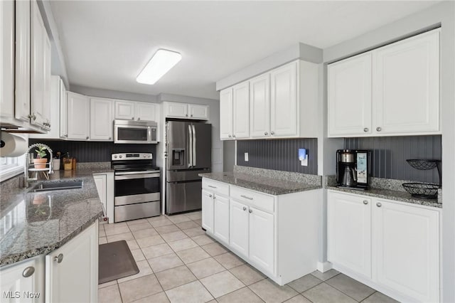 kitchen featuring a sink, appliances with stainless steel finishes, white cabinets, and light tile patterned floors