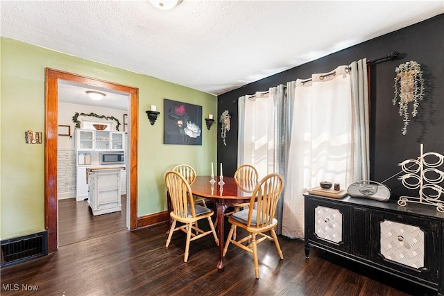 dining space with baseboards, dark wood-style floors, visible vents, and a textured ceiling