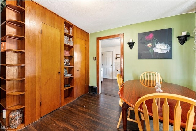 dining area with a textured ceiling and dark wood-style floors