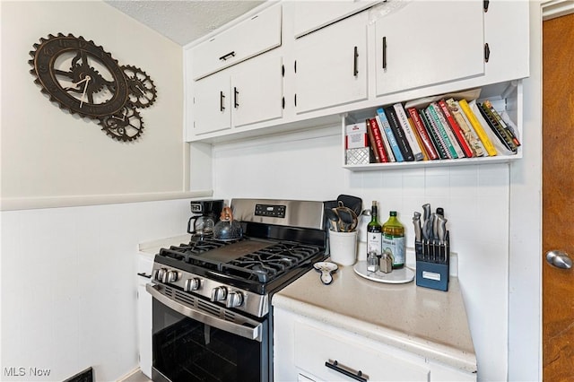 kitchen with white cabinets, gas stove, a textured ceiling, and light countertops