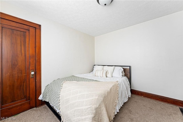 bedroom featuring light carpet, baseboards, and a textured ceiling