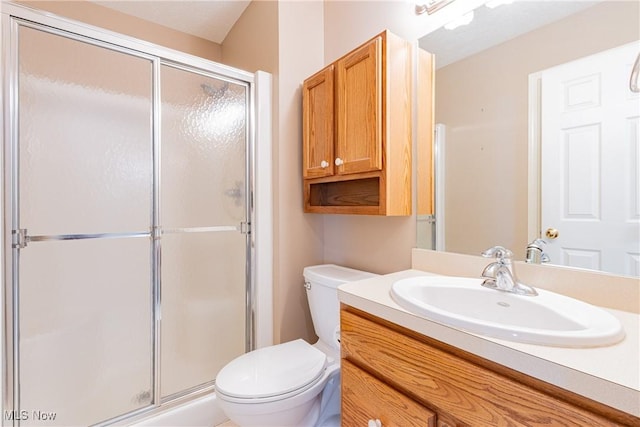 bathroom with a stall shower, toilet, and vanity