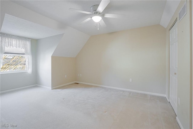 additional living space with visible vents, baseboards, light colored carpet, vaulted ceiling, and a ceiling fan