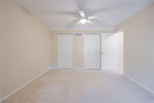 unfurnished bedroom featuring visible vents, baseboards, light colored carpet, and a ceiling fan