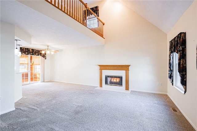 unfurnished living room with a high ceiling, a fireplace with flush hearth, carpet, and visible vents