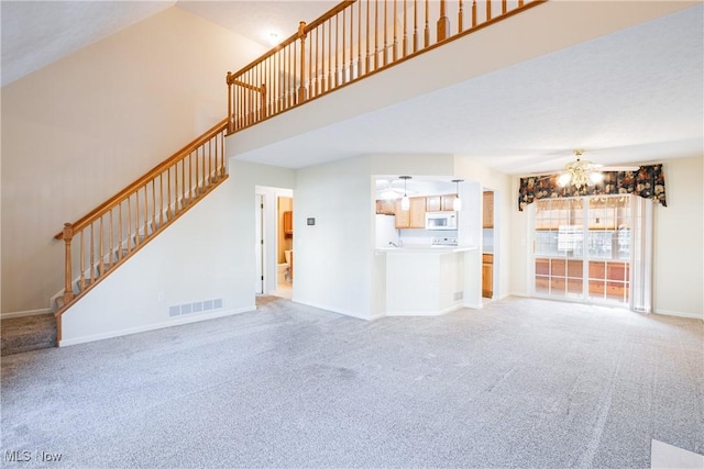 unfurnished living room featuring visible vents, light carpet, stairway, baseboards, and a chandelier