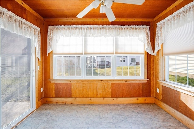 unfurnished sunroom featuring wood ceiling and a ceiling fan