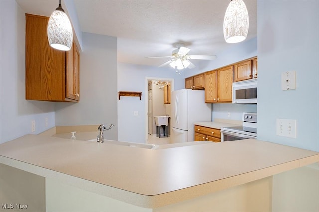 kitchen with white appliances, brown cabinetry, a peninsula, ceiling fan, and a sink