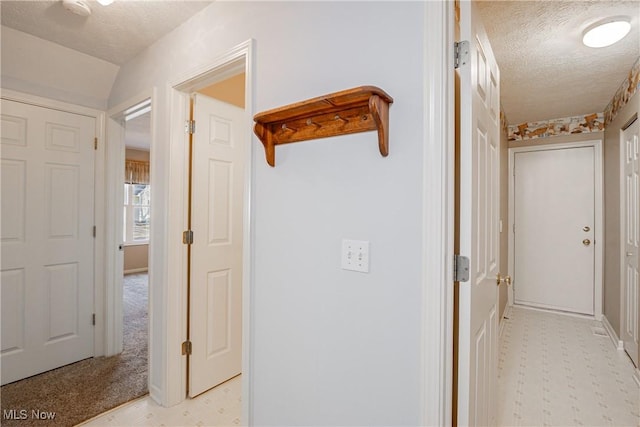 corridor with light floors and a textured ceiling