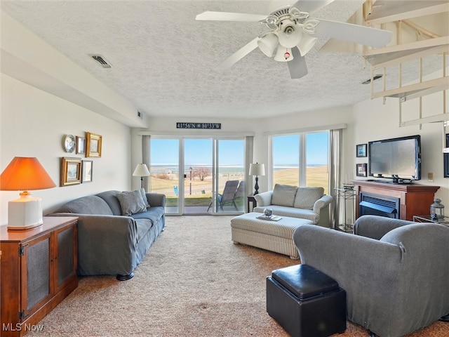 living room featuring visible vents, carpet floors, plenty of natural light, and a ceiling fan