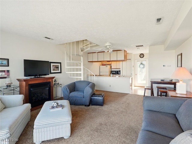 living area featuring a ceiling fan, stairs, carpet, and visible vents