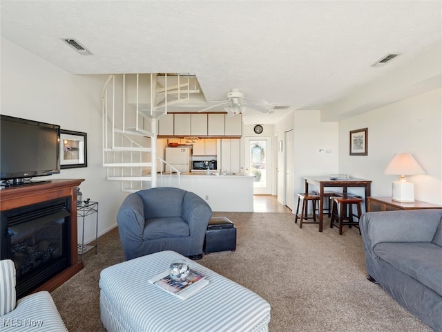 living area with visible vents, a ceiling fan, and carpet floors