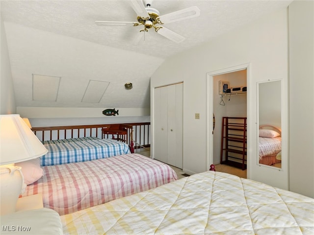 bedroom featuring two closets, a textured ceiling, a ceiling fan, and vaulted ceiling