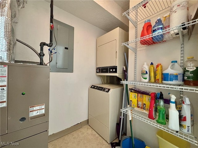 laundry area featuring laundry area, electric panel, baseboards, and stacked washing maching and dryer