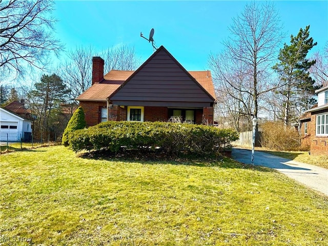 view of home's exterior with brick siding, a lawn, a chimney, and fence