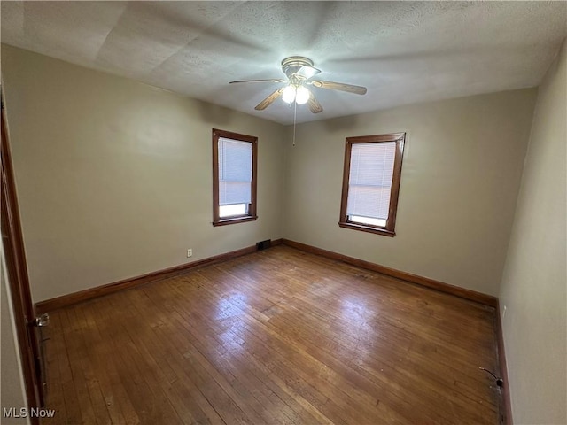 spare room with a ceiling fan, baseboards, and wood-type flooring