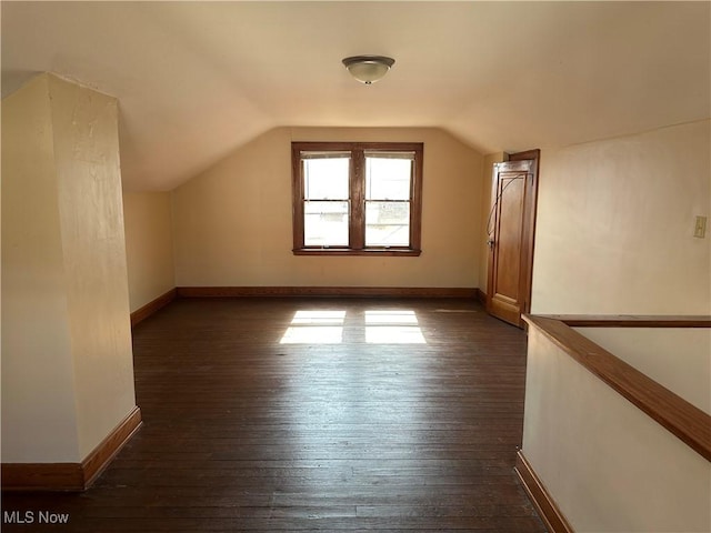 bonus room with dark wood finished floors, vaulted ceiling, and baseboards