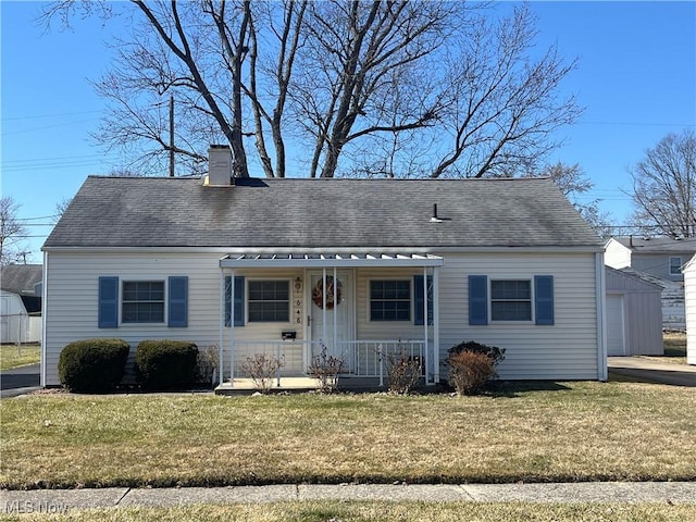 view of front of property with a chimney, covered porch, an outdoor structure, and a front lawn