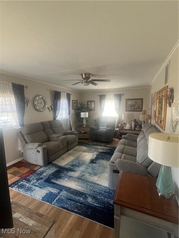 living area with crown molding, wood finished floors, visible vents, and ceiling fan