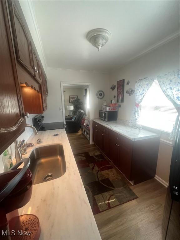 kitchen featuring dark wood-style floors, stainless steel microwave, light countertops, and a sink