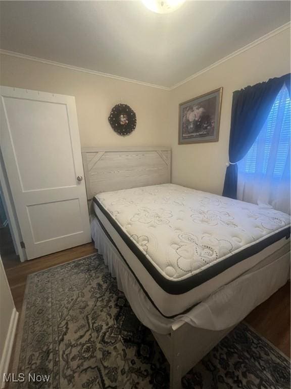 bedroom with wood finished floors and ornamental molding