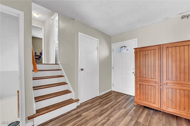 entrance foyer with a textured ceiling, stairs, and light wood finished floors