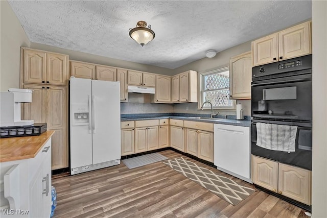 kitchen featuring white appliances, light brown cabinets, light wood-style flooring, a sink, and under cabinet range hood