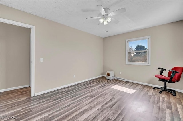 spare room with visible vents, baseboards, ceiling fan, wood finished floors, and a textured ceiling