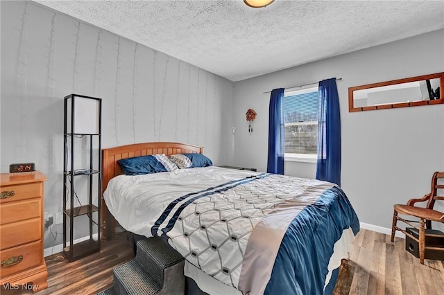 bedroom featuring wood finished floors, baseboards, and a textured ceiling