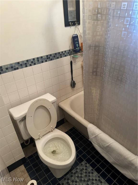 full bathroom featuring toilet, tile walls, shower / tub combo with curtain, and tile patterned flooring