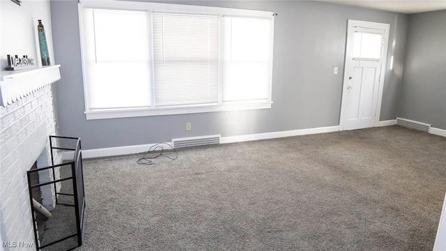 carpeted empty room with visible vents, a fireplace, and baseboards