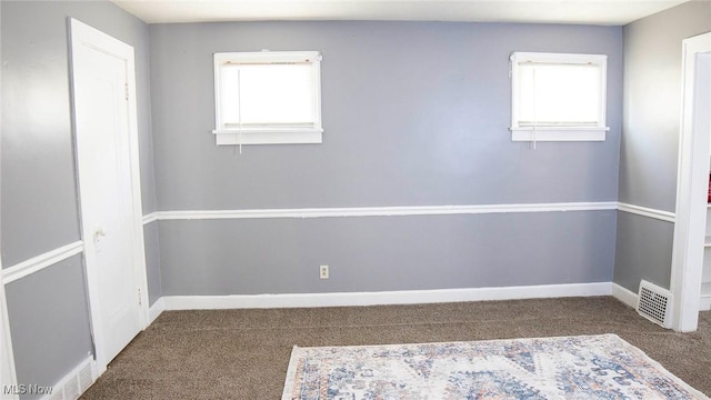 carpeted spare room with a wealth of natural light, visible vents, and baseboards