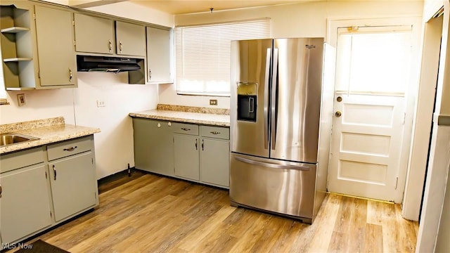 kitchen with light wood finished floors, open shelves, gray cabinets, light countertops, and stainless steel fridge